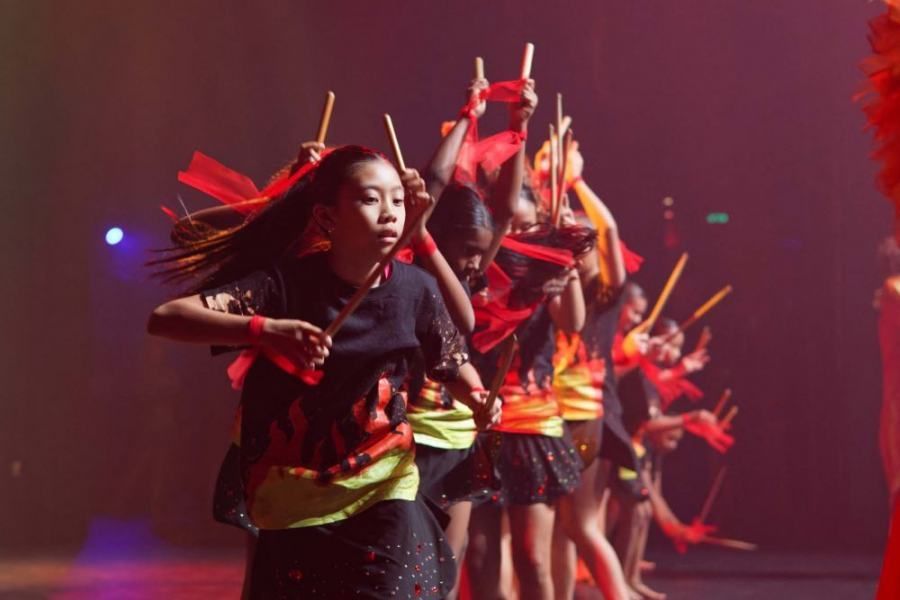 A group of children are performing a dance with sticks