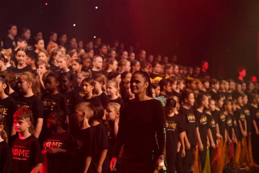 A man is standing in front of a large group of children.