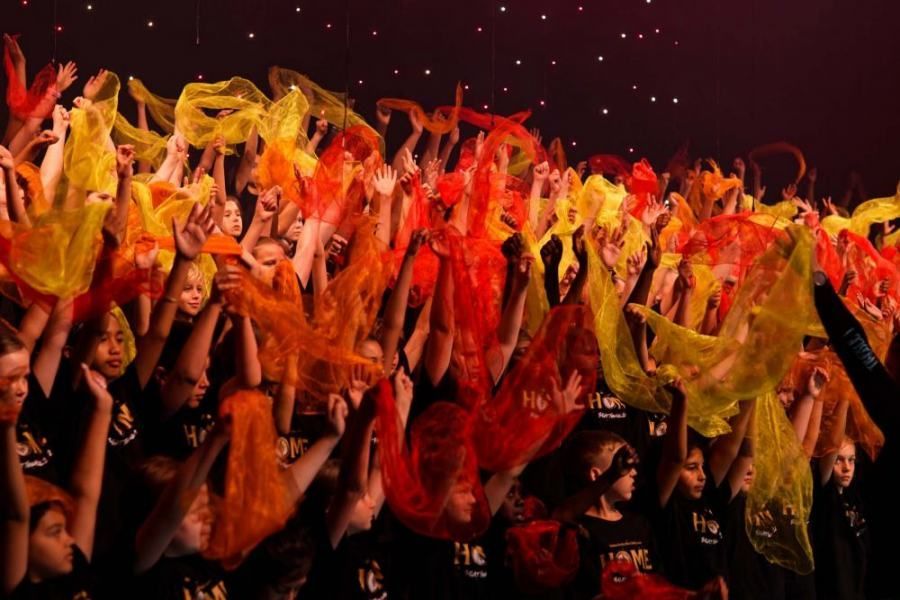 A group of people are dancing in a dark room with their hands in the air.