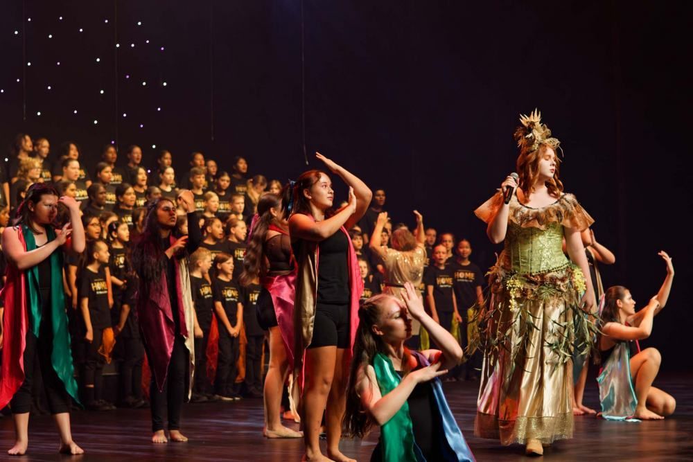 A group of people are dancing on a stage in front of a choir.