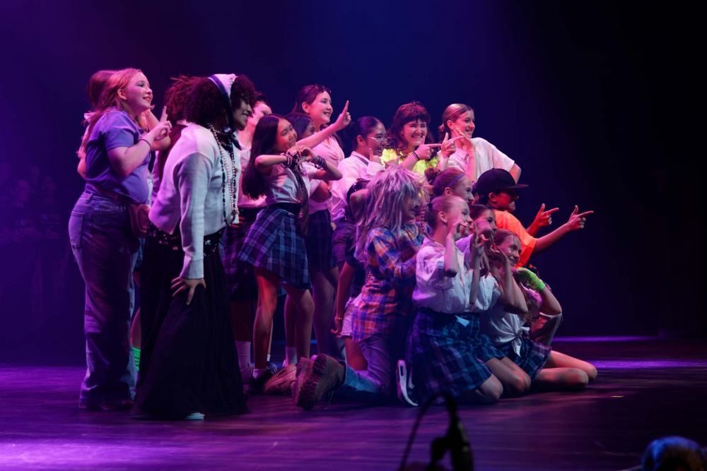 A group of people are standing on a stage with purple lights.