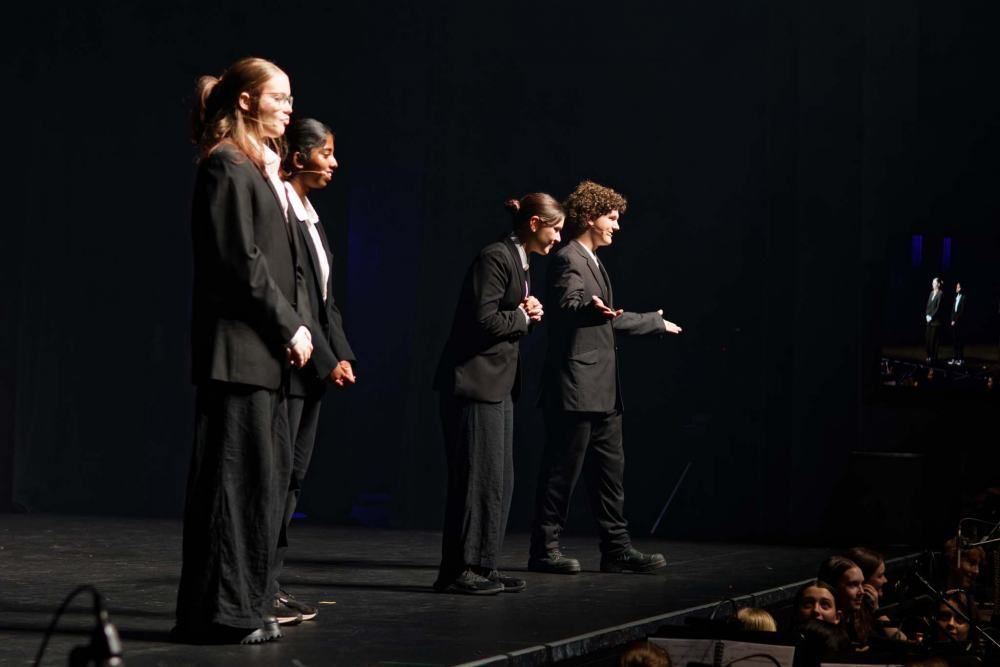 A group of people are standing on a stage in front of a crowd.