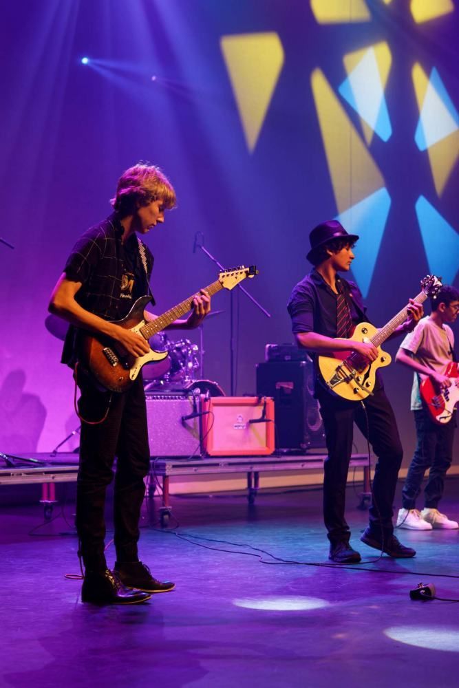 A group of young men are playing guitars on a stage.