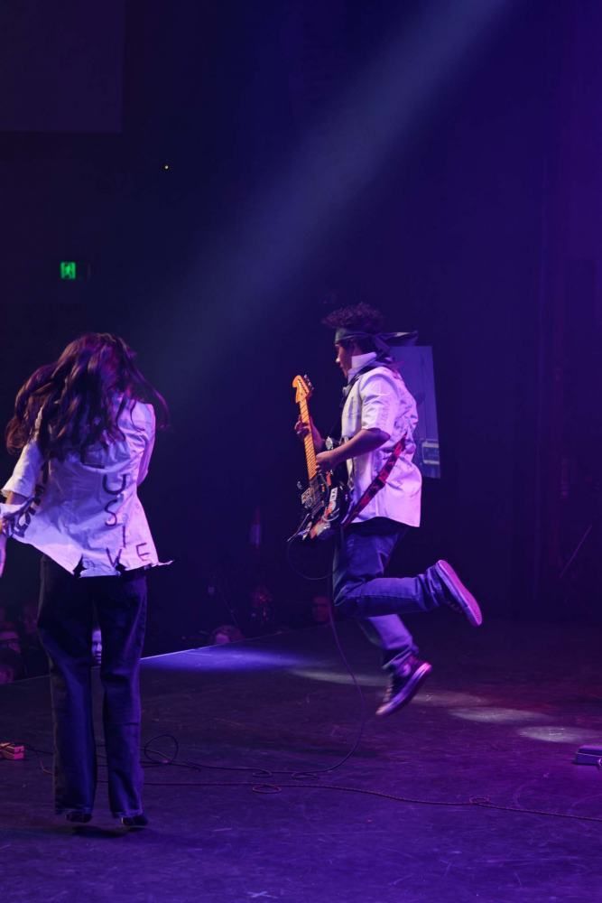 A man and a woman are dancing on a stage while a man plays a guitar.