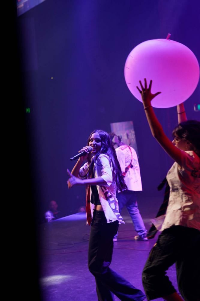 A group of people are playing with balloons on a stage.