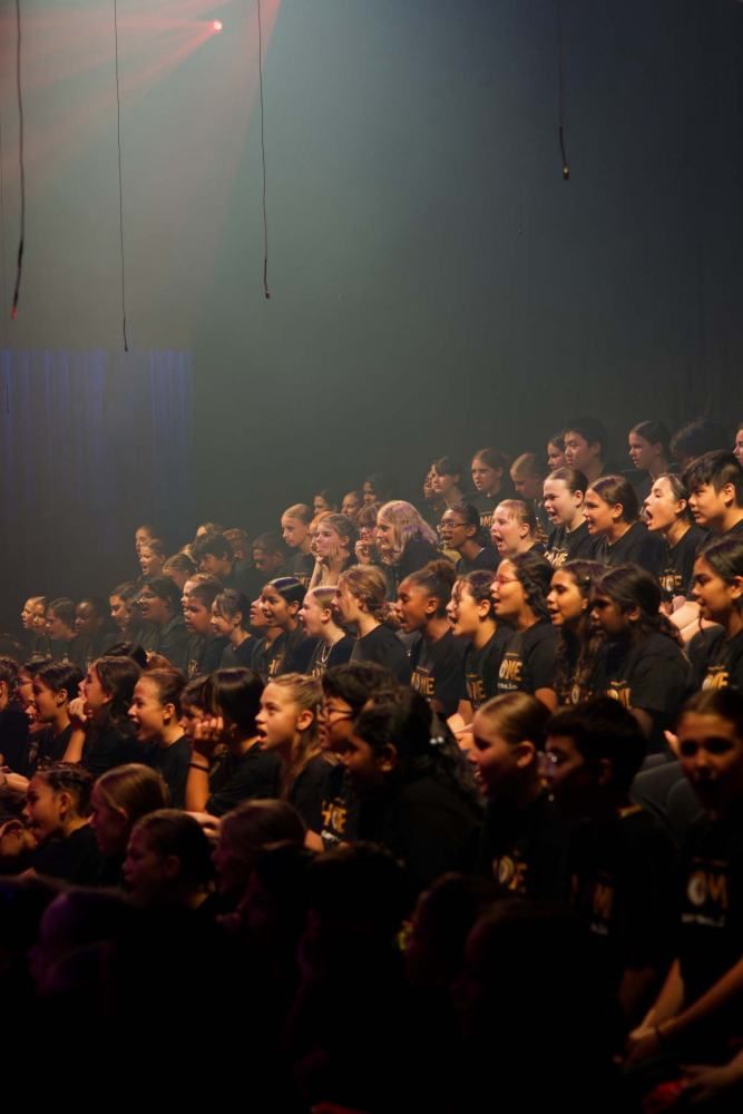 A large group of people are sitting in a dark room.