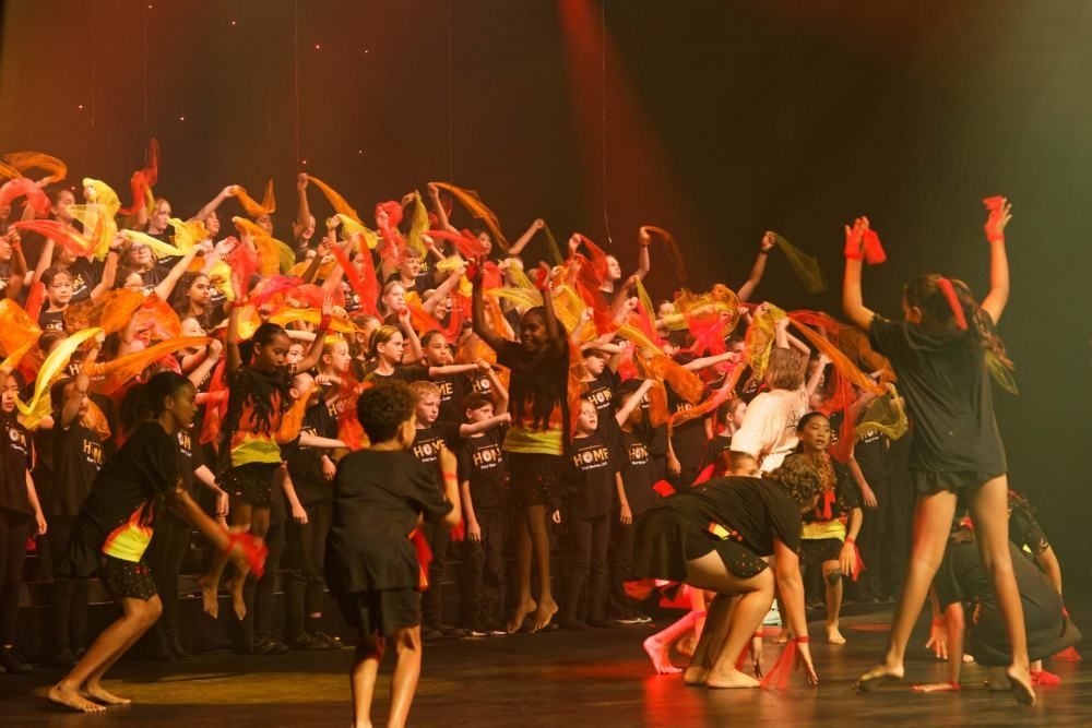 A large group of people are dancing on a stage.