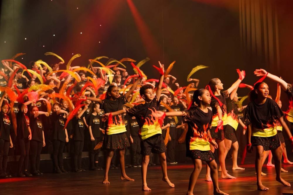 A group of children are dancing on a stage.