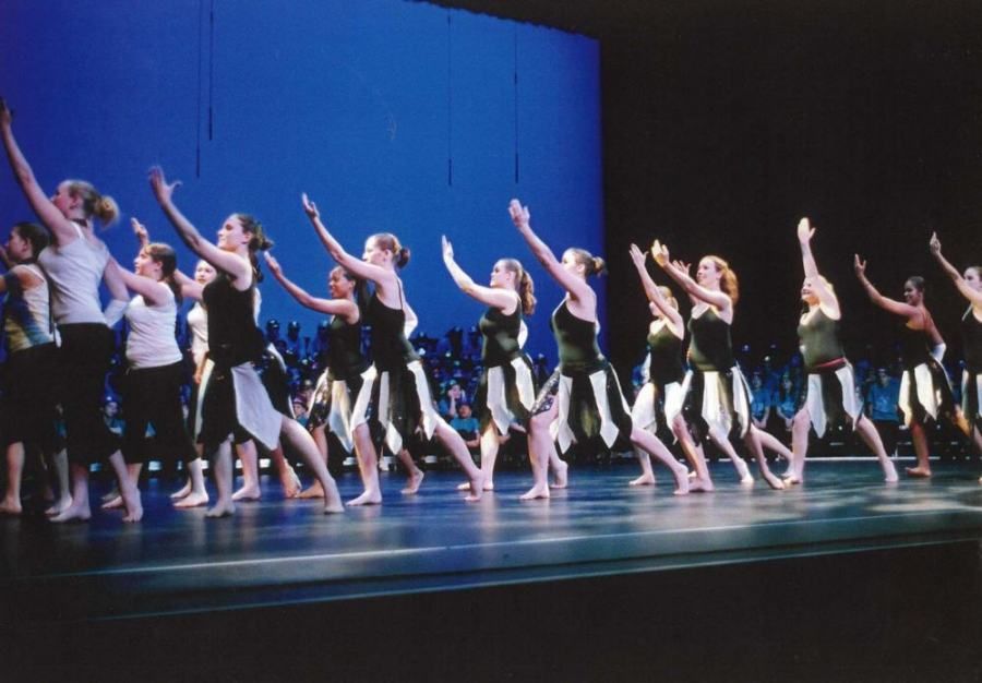 A group of women are dancing on a stage with their arms in the air