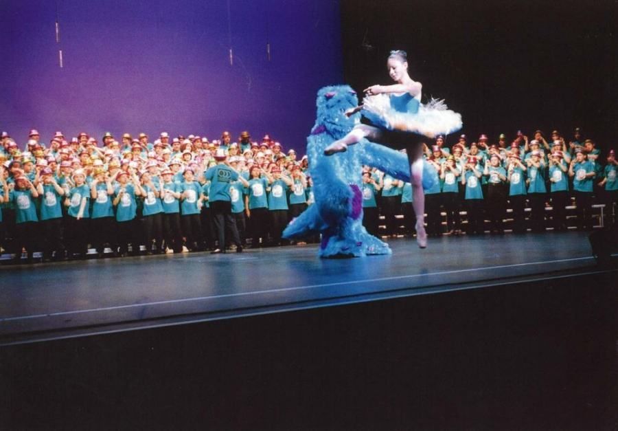 A ballerina is dancing on a stage in front of a crowd