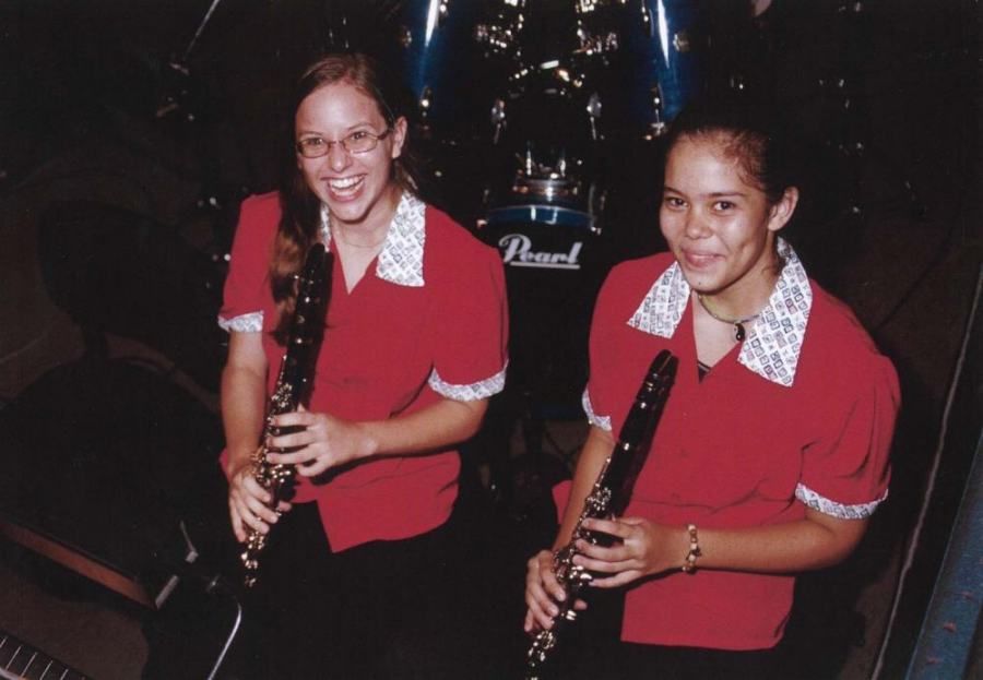 Two girls playing clarinets in front of a pearl drum set