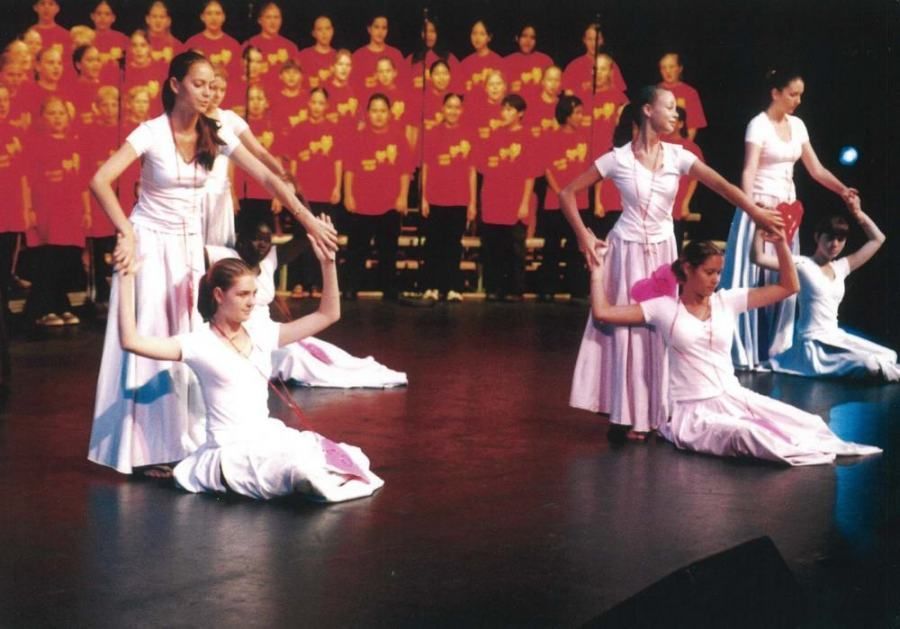 A group of women are dancing on a stage in front of a choir