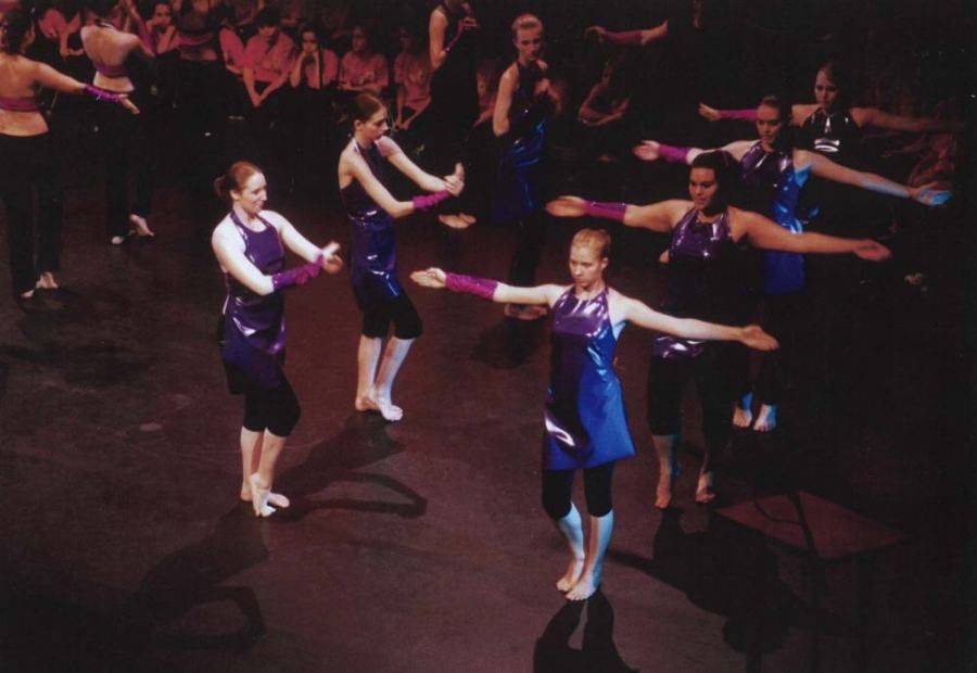 A group of women are dancing on a stage with their arms outstretched