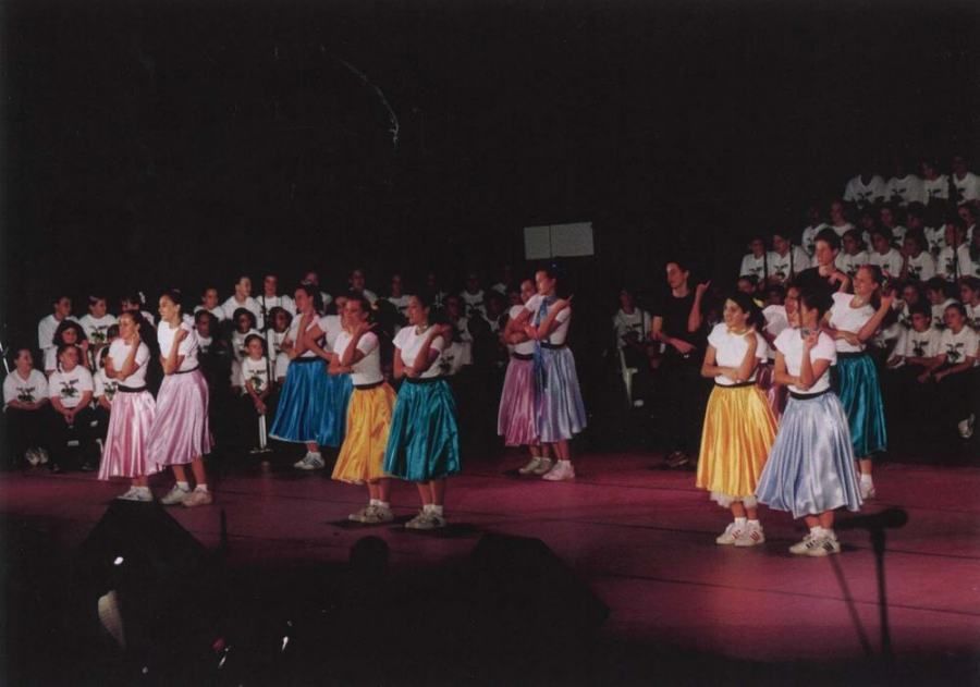 A group of girls are dancing on a stage in front of a crowd
