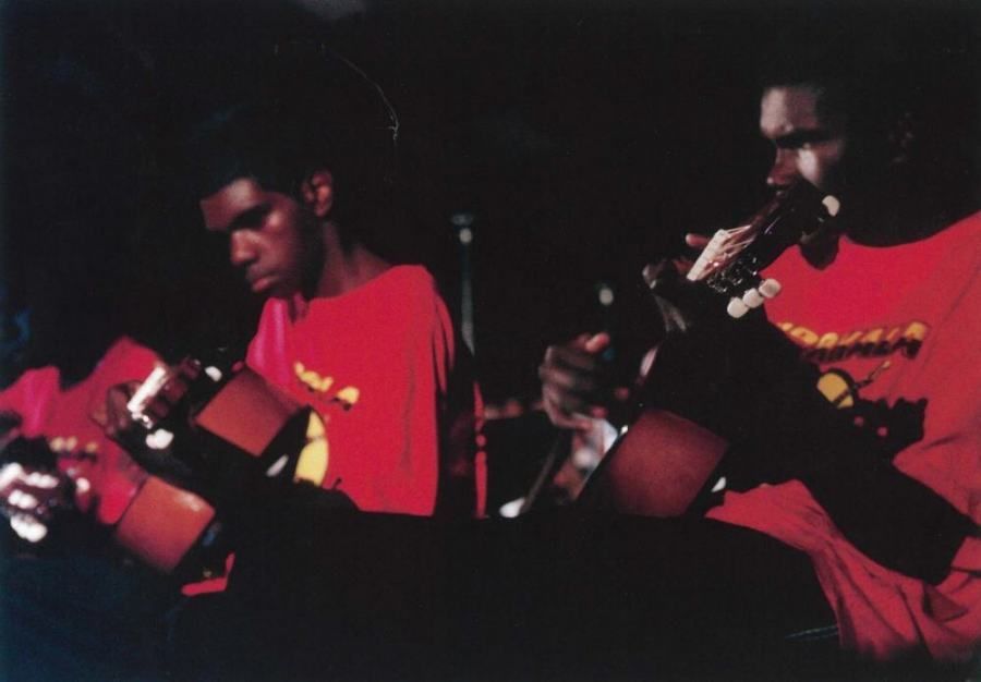 Two men in red shirts are playing musical instruments