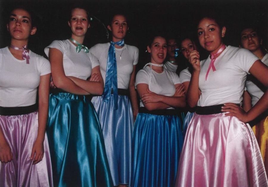 A group of girls wearing satin skirts and white shirts