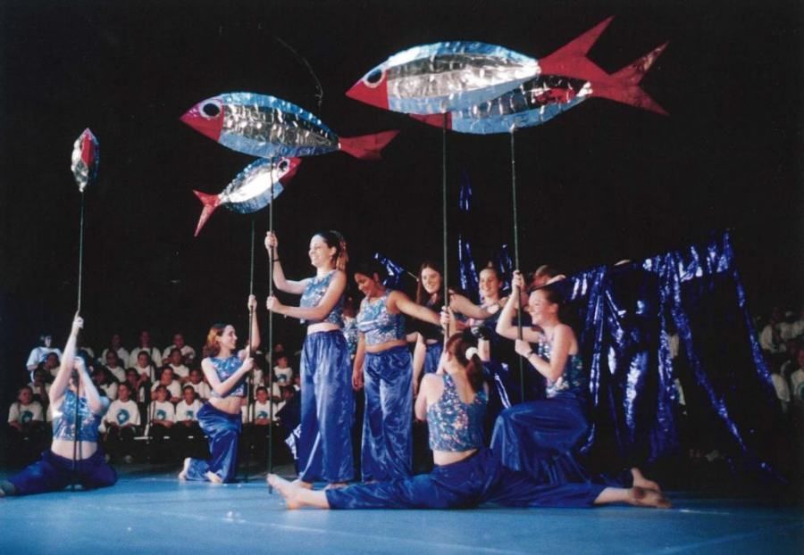 A group of women holding fish shaped balloons on a stage