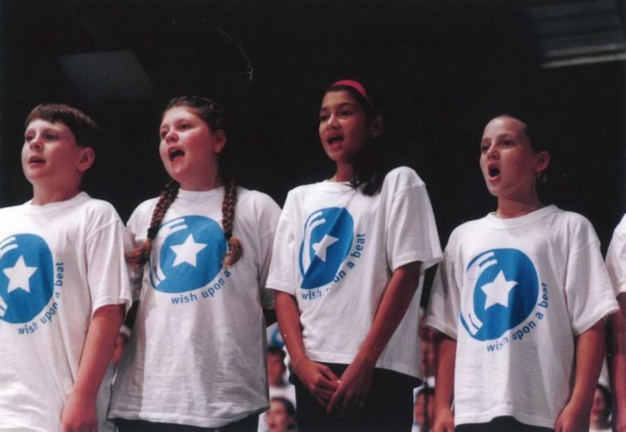 A group of children wearing white shirts with blue stars on them