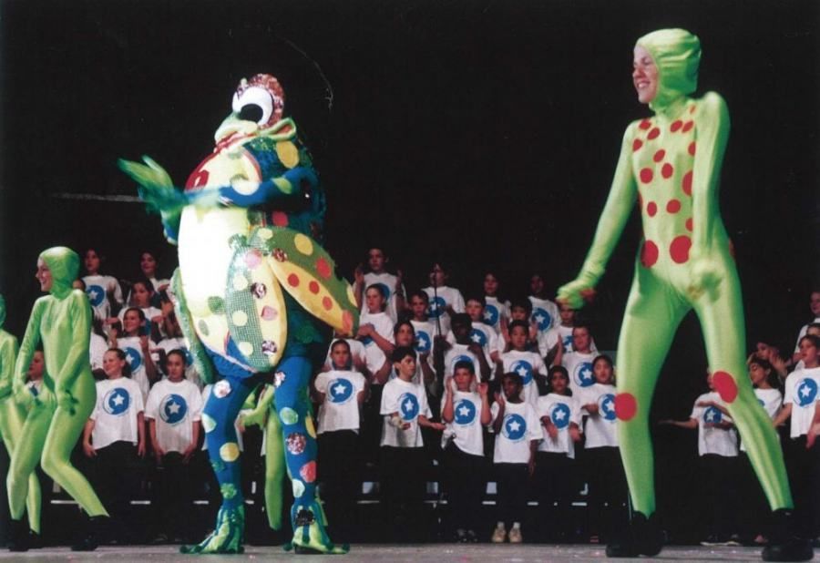 A group of people in frog costumes are dancing on a stage