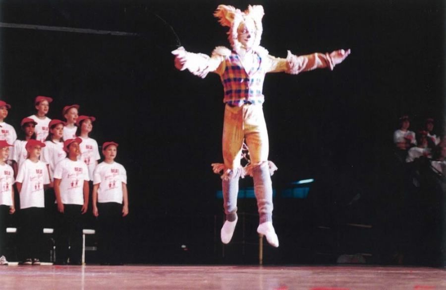 A person in a scarecrow costume is jumping in the air