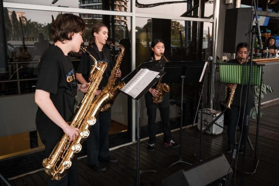 A group of people playing saxophones in front of a window