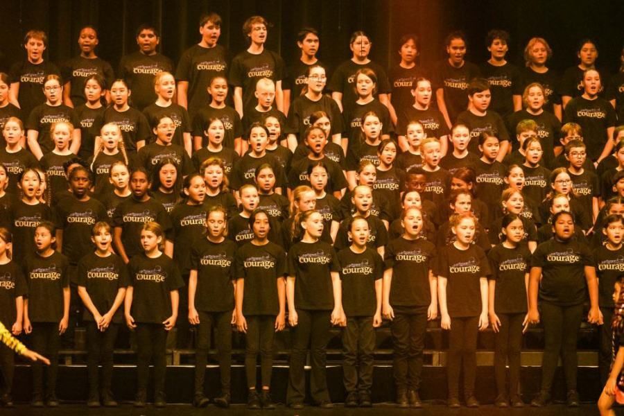 A large group of children are singing in a choir
