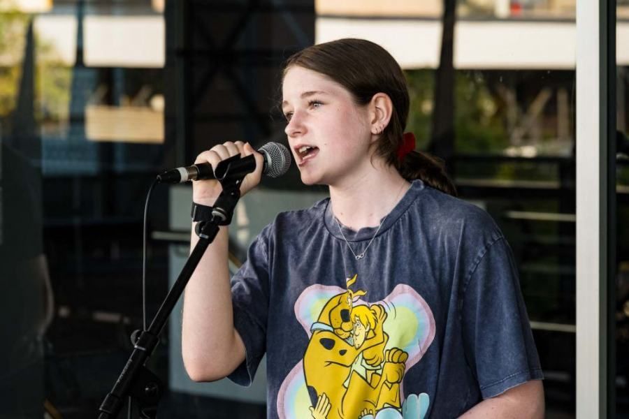 A young girl is singing into a microphone while wearing a winnie the pooh shirt.