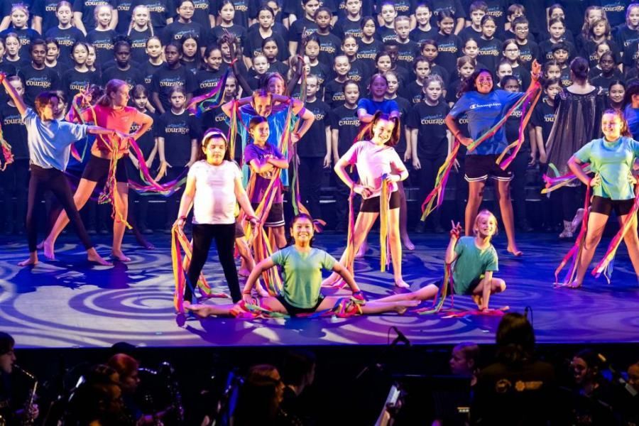 A group of young girls are dancing on a stage in front of a crowd.