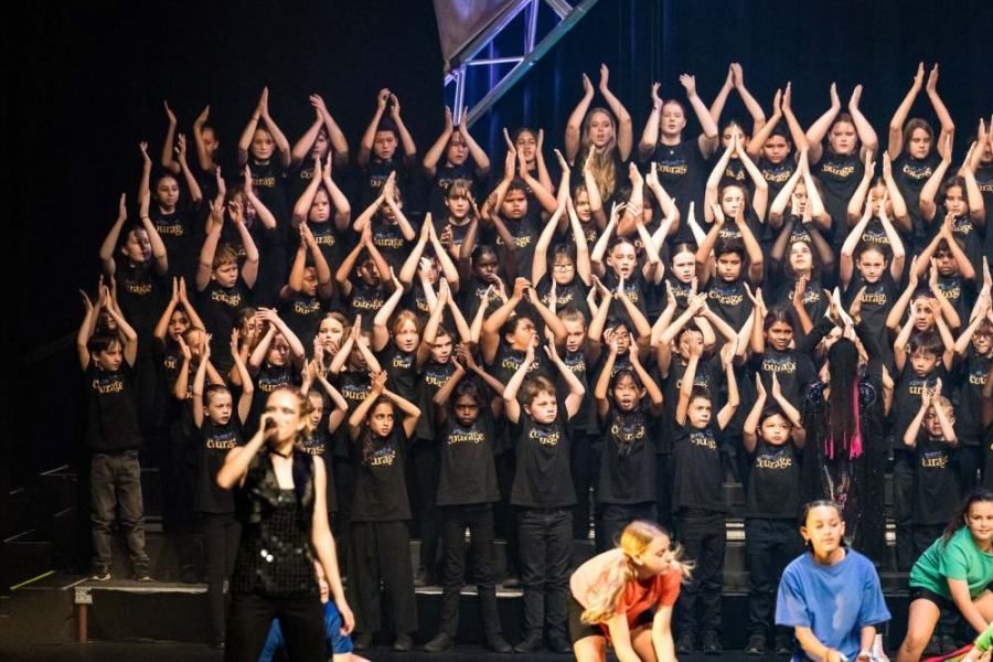 A large group of people are standing on a stage with their hands in the air.