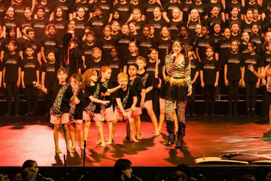 A woman singing into a microphone in front of a large choir