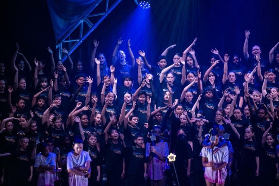 A large group of people are standing on a stage with their hands in the air.