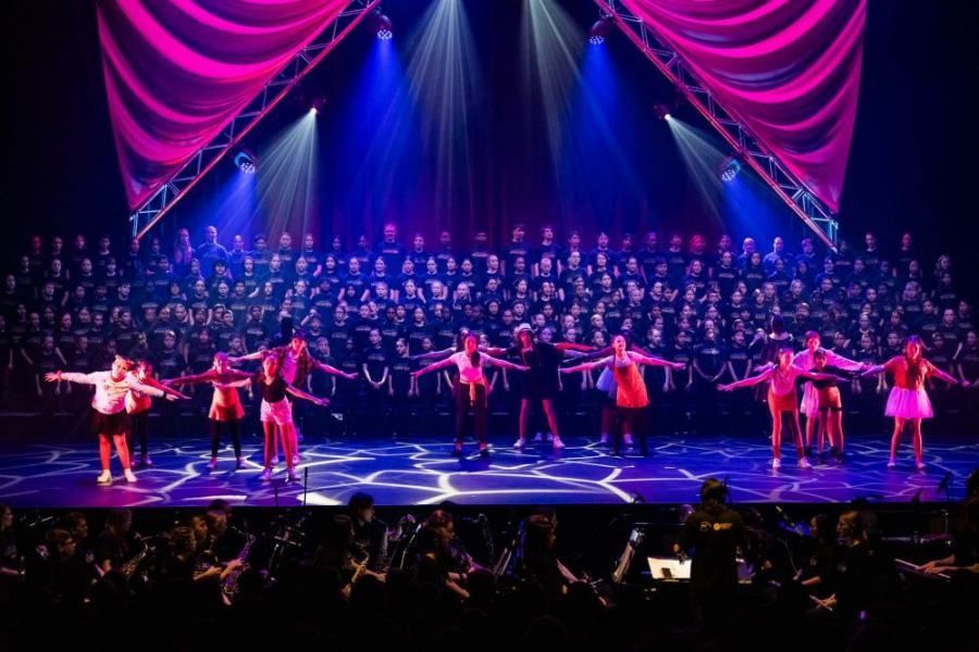 A group of people are dancing on a stage in front of a large choir.