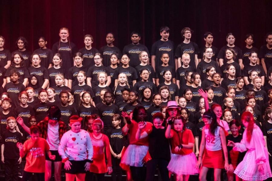 A large group of children are posing for a picture on a stage.