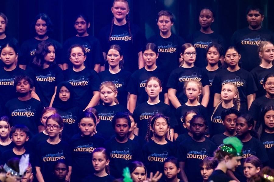 A large group of children wearing black shirts with the word courage on them.
