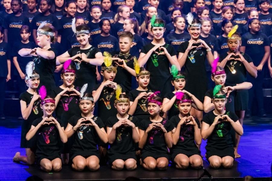 A large group of children are posing for a picture on a stage.