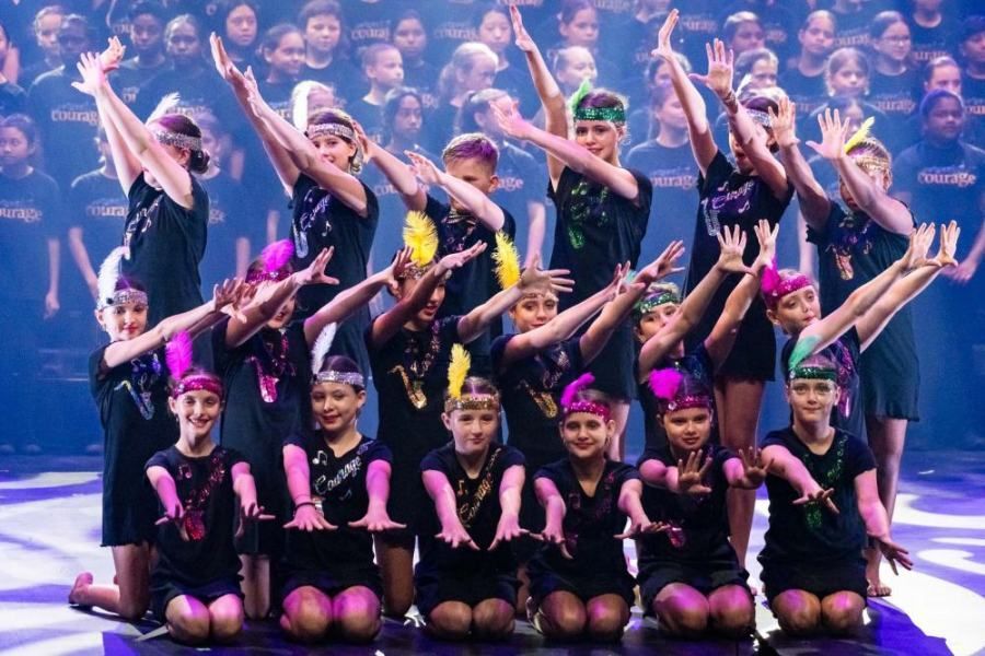 A group of children are posing for a picture on a stage.