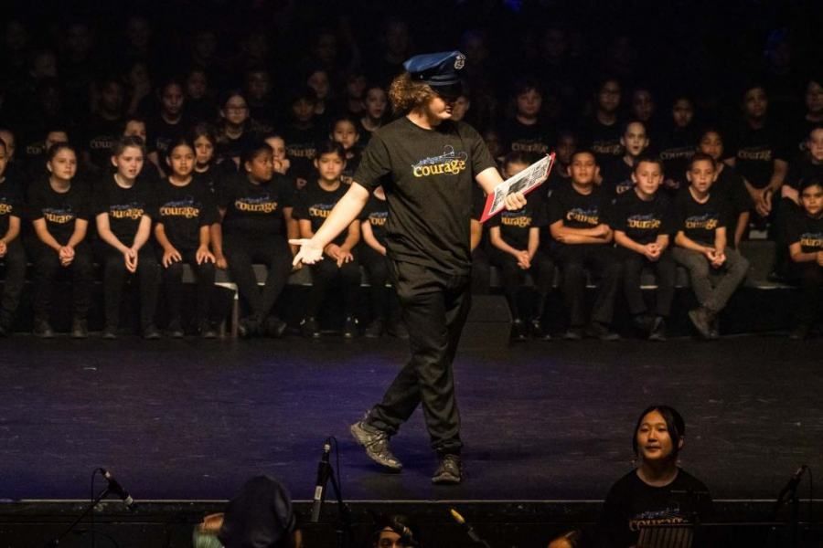 A man is standing on a stage in front of a crowd of children.
