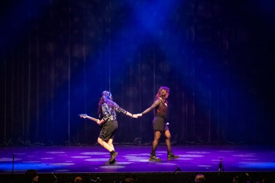 Two women are dancing on a stage holding hands.
