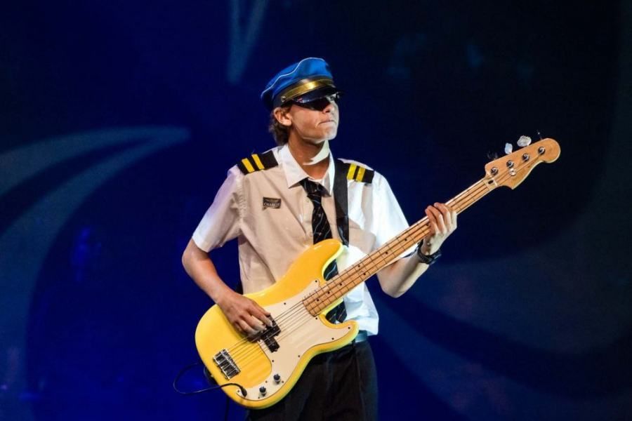 A man in a pilot costume is playing a guitar on stage.