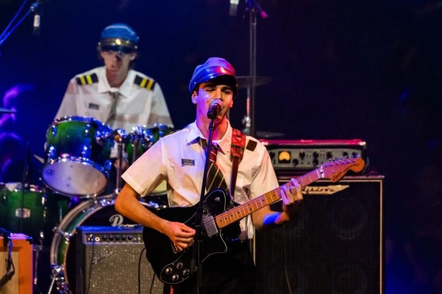 A man is playing a guitar and singing into a microphone on a stage.
