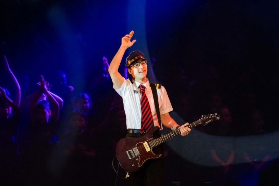 A man is playing a guitar on a stage in front of a crowd.