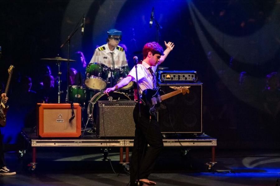 A man is playing a guitar on a stage in front of an orange amp