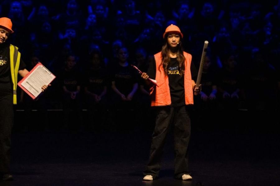 A man and a woman are standing on a stage in front of a crowd.