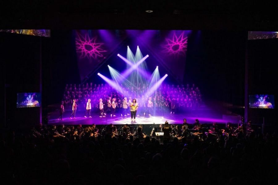 A group of people are standing on a stage with purple lights.