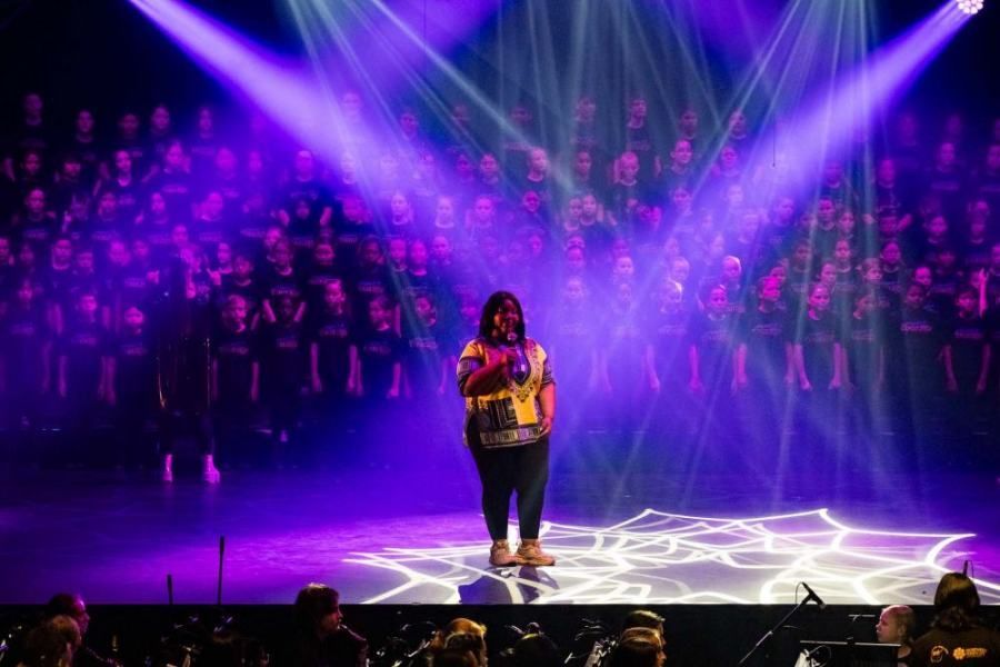 A woman is standing on a stage in front of a choir.