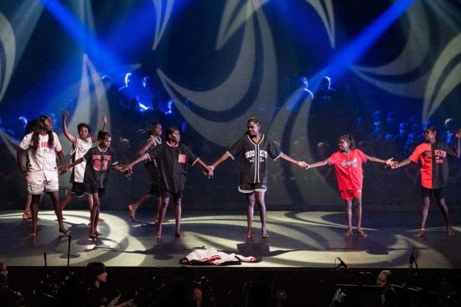A group of people are holding hands on a stage.