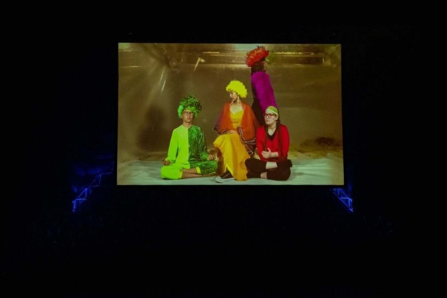 A group of people are sitting on the floor in front of a screen.