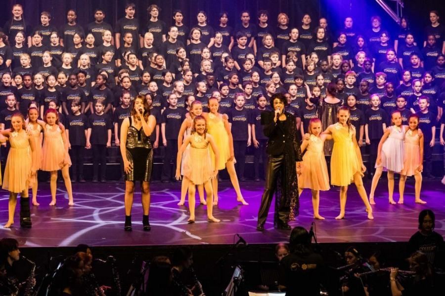A group of people are standing on a stage in front of a large choir.