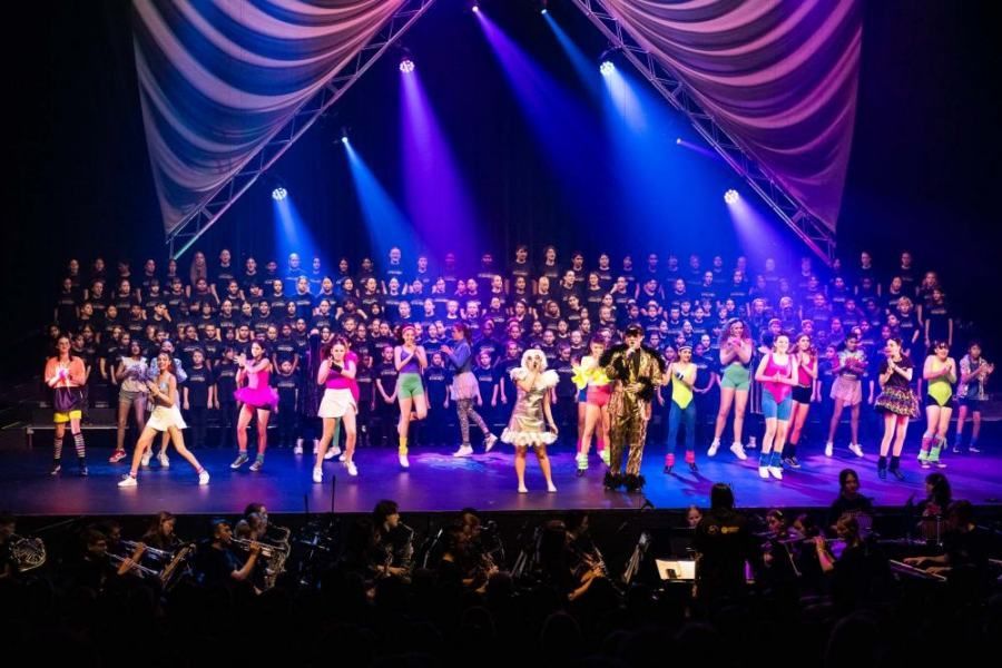 A large group of people are standing on a stage in front of a crowd.