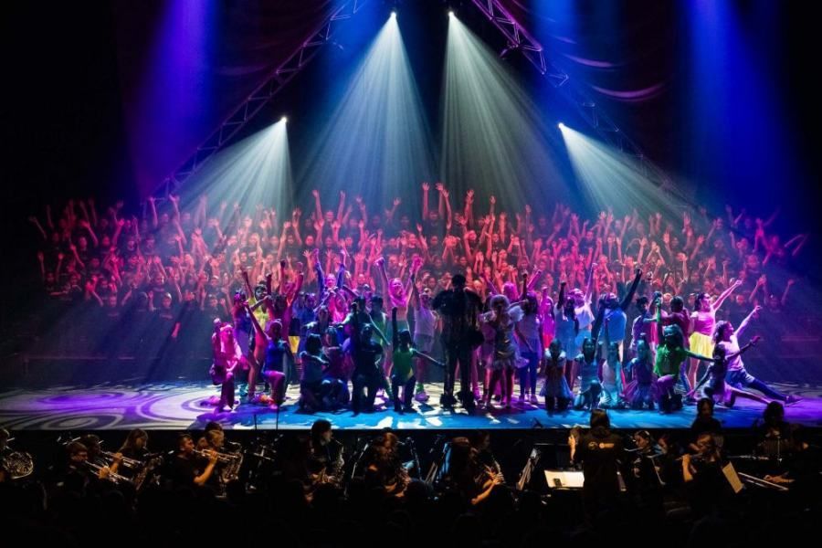 A large group of people are standing on a stage in front of a crowd.